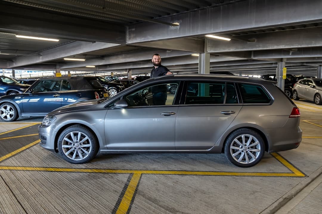 Man standing by a silver station wagon in parking garage — Photo by Holiday Extras on Unsplash